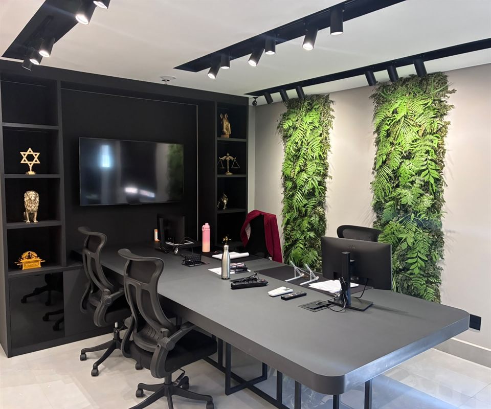 Sala de reuniões do escritório Comparotto & Mendes com estante em laca preta, televisão e jardim vertical